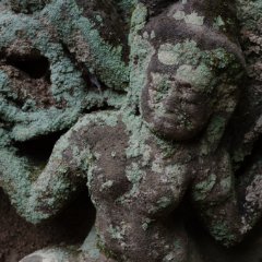 Banteay Kdei - carving details Kleine, mit Flechten bedeckte Statue auf einem Flachrelief / Small statue coverd with lichen on a bas relief